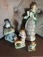 Overview of the 4 Occupied Japan porcelain figurines together on a couch