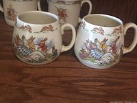 Side-by-side photo of two Bunnykins mugs with bunny illustrations and handles