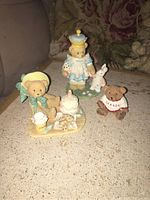 Photo showing all three figurines on a sofa table featuring the queen bear, tea time bear, and unmarked Canada shirt bear.