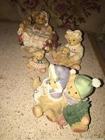 Four figurines on a fabric surface, showing all from front with some overlap