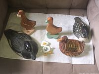 Top-down view showing all six duck-related items arranged on white towel on brown couch.