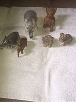 Photo showing all six elephant figurines placed on a towel, including a large gray ceramic elephant, a large brown carved wooden elephant, and four smaller diverse figurines.