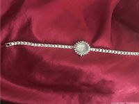 Full view of the ladies Elgin watch showing the full length stone-studded bracelet and oval watch face.