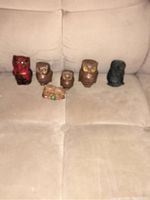 All six owl figurines arranged on beige couch showing size and color variations.