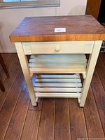 Front view of the chopping block island showing butcher block top, drawer, and bottom slatted shelves.