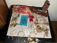 Overview of assorted dream catchers, fabric leis, and decorative vase on white surface