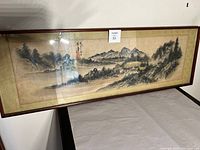 Full view of framed silk screen depicting a Japanese landscape painting, showing mountains, water, and trees.