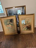 Photo showing the large mirror and two framed flower watercolor paintings together against a wall.