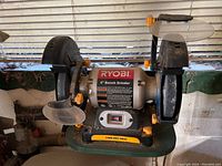 Photo showing a Ryobi 6-inch bench grinder with dual grinding wheels and protective guards on each side.