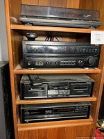 Wooden shelf unit with four audio components: Technics turntable on top, Pioneer tuner below, Onkyo cassette player below that, and Onkyo DVD player on bottom.
