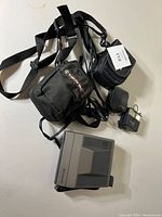 Photo of Pentax light meter with charger and carrying case, camera bags visible
