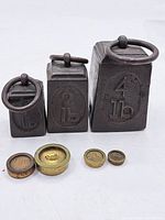 Cast iron and brass weights arranged on a white surface showing all seven pieces, including the 1 lb, 2 lb, and 4 lb cast iron weights and four smaller brass weights.