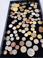 Overview image showing a variety of vintage world coins in different metals and sizes arranged in a display tray.