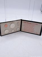Photo of open black display case showing six coins and informational insert titled 'The Second Century' about the 1967 Canadian Centennial.