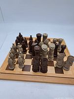 Full view of chess pieces arranged on the chessboard, showing the position and design of dark brown and off-white pieces.