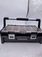 Closed Husky toolbox with clear top and metal latches, black and grey plastic body.