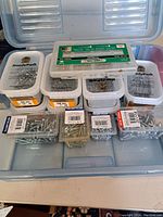 Plastic containers filled with assorted screws, nails in various sizes and types