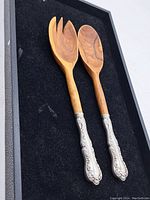 Pair of vintage Birks sterling silver handled salad servers on black surface showing full utensils.