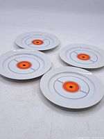 Four vintage Thomas Germany plates from the 1970s with a distinctive orange and black concentric circle geometric design on white background laid on a white surface.