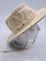 Side profile of the beige Tilley Airflo hat featuring ventilation mesh and chin strap on a mannequin head.
