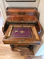 Front view with fall-front lid open revealing interior compartments, writing surface and keys on leather pad