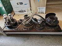 Overall view of wooden chassis with four cylindrical metal coil cans, tube sockets, attached wiring and straps