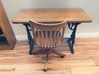 Full front view of antique wooden top side table with cast iron base and antique oakwood swivel chair.