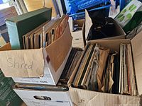 Three cardboard boxes filled with assorted vintage LP vinyl records showing wear and tear, stored vertically with various album sleeves visible