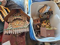 Overview of four clocks, one outside and three inside a plastic bin, chains and parts visible