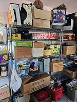 Full view of metal shelving unit with multiple cardboard boxes of varying sizes and purposes, including some labeled and marked fragile or for refrigeration.