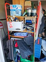 Shelf showing multiple items including dog pads, stuffed bear, foldable chairs, and camping propane canisters.