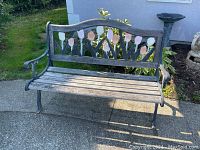 Full front view of the garden bench showing cast iron frame and wooden slat seat with painted floral backrest.