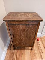 Front view of vintage oak small cabinet with closed door showing wood grain.