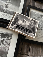 Photo showing the boxed set of Ansel Adams House Photographs postcards and two black-framed photos, one with cactus and the other canyon scene.