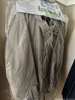 Tan men's Eddie Bauer jacket in protective plastic covering shown hanging on a wall.