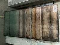 Full view of framed abstract art with horizontal bands of dark green, brown, beige, and grey, showing overall worn condition.