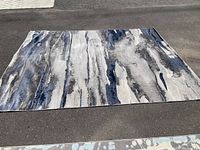 Full view of rectangular area rug laid flat on asphalt