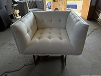 Front view showing tufted white leather seating and metal base with angled legs.