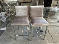Front view of two metal frame chairs with light gray velveteen upholstery showing seat and backrest.