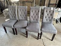 Front view of four grey button-tufted chairs in a row