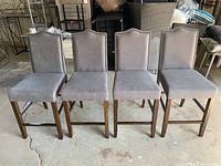 Four upholstered chairs/stools with light grey fabric and wood legs; minor scratches visible on legs.