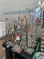 Front and side views showing assortment of untested table lamps with metal and glass bases, no shades, displayed on a table near a mirror.