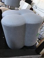 Side angle showing the clove-shaped top and smooth synthetic fabric upholstery with nailhead trim detail at the bottom.