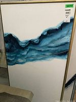 Full view of textured abstract print on canvas in a wooden frame, showing top left corner and part of blue abstract design.