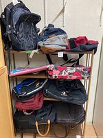 Photo showing assortment of bags and backpacks on shelves, various colors and styles including black, gray, red, floral design