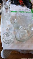 Top down view of assorted crystal and glassware showing the layout and condition on white cloth.