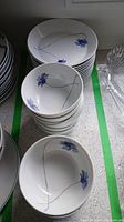 Multiple white ceramic bowls with blue floral and line design stacked in two stacks on a countertop.