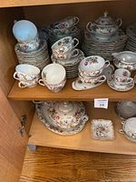 Upper cabinet shelf showing stacked place settings and cups
