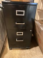 Front view of black two drawer metal filing cabinet, closed drawers with silver handles and label holders.