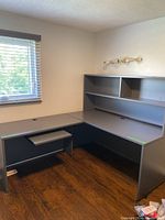 Photo of the full L-shaped desk with hutch in a room near window showing configuration and material.